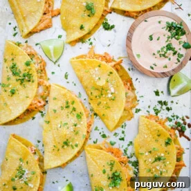 Sheet pan with cooked shredded chicken tacos.
