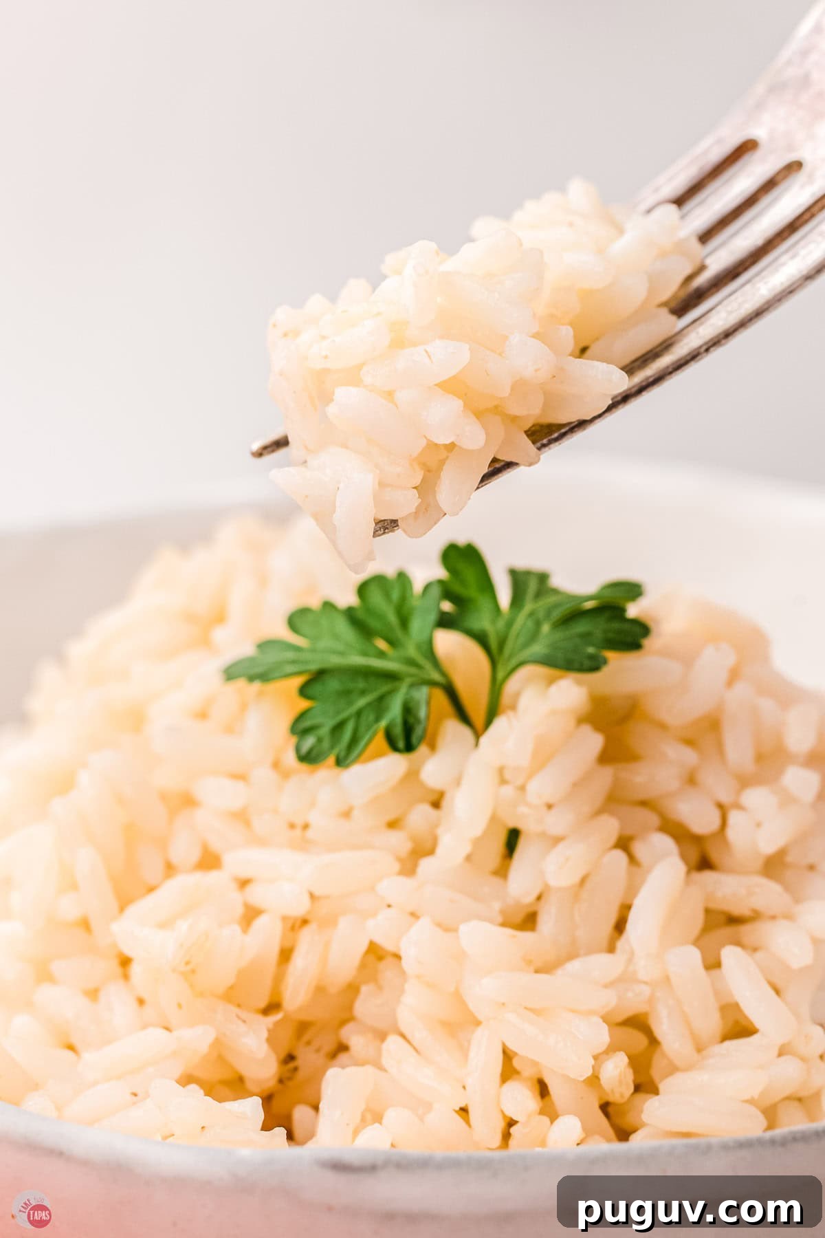 fork with bite of baked white rice over a bowl of rice