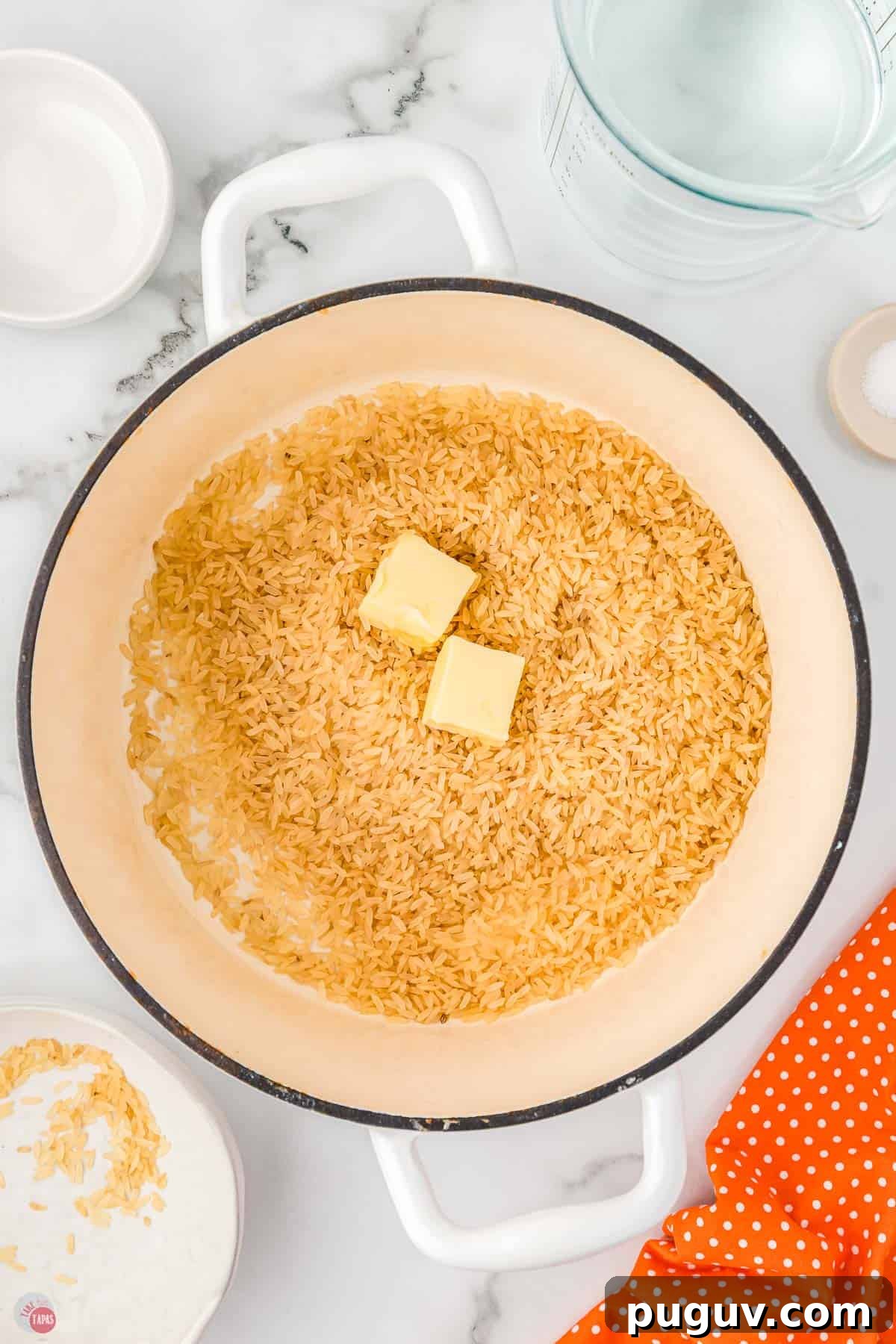 white pot with uncooked rice and two pats of butter