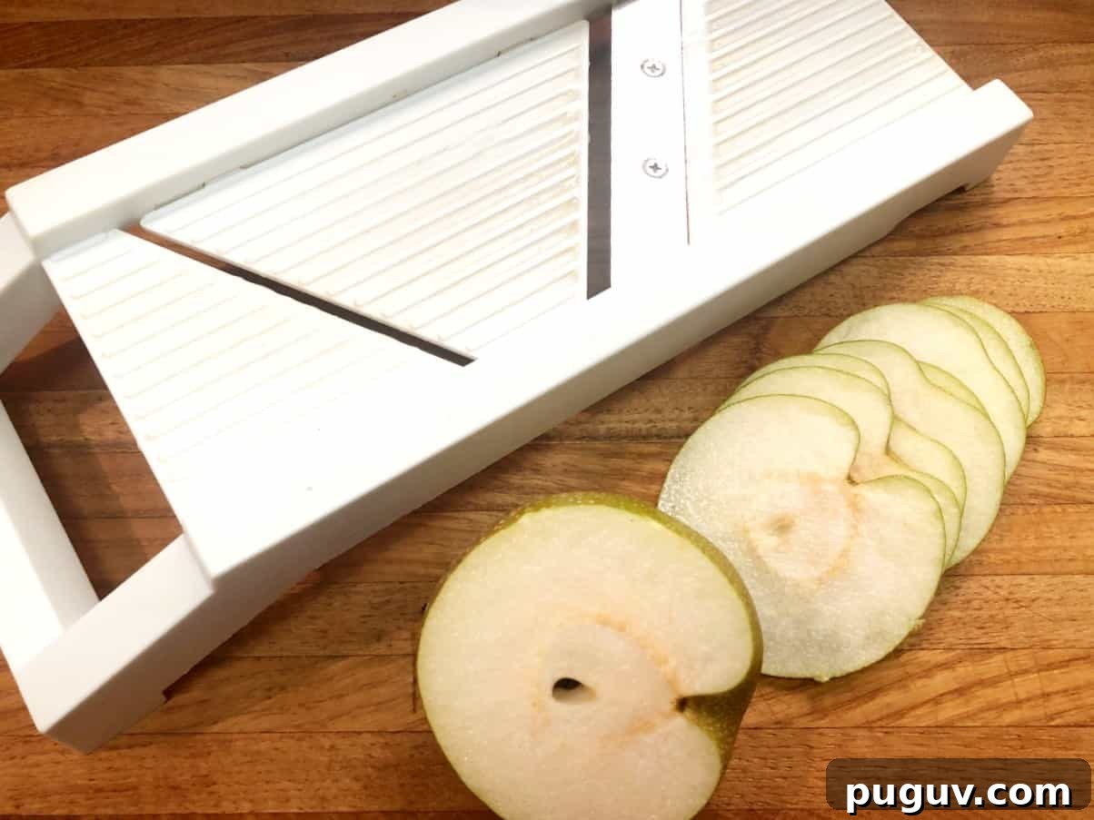 sliced asian pears with mandolin on a cutting board.
