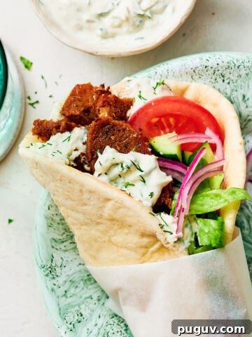 A Greek-inspired Vegan Gyros with tzatziki and tomato on a dinner plate.