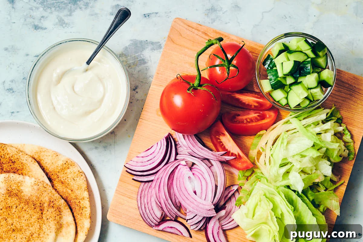 Veggies on a cutting board with shawarma sauce and pita.