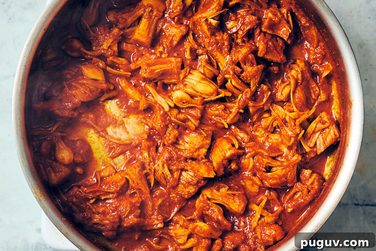 Shredded jackfruit with seasoning in a pan for vegan shawarma recipe.