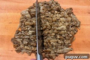 Smoked Baba Ganoush Recipe: Creamy Charred Eggplant Dip 12 Chopping the flesh of roasted eggplants on a wooden cutting board.