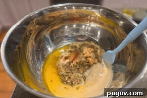 Smoked Baba Ganoush Recipe: Creamy Charred Eggplant Dip 13 Large metal mixing bowl filled with chopped eggplant, tahini, and olive oil.