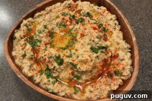 Smoked Baba Ganoush Recipe: Creamy Charred Eggplant Dip 14 Wooden bowl filled with baba ganoush and topped with olive oil drizzle, chopped parsley, and a dusting of paprika.