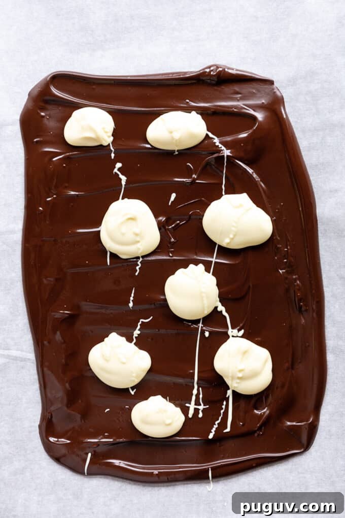 dark chocolate with dollops of white chocolate spread onto parchment paper
