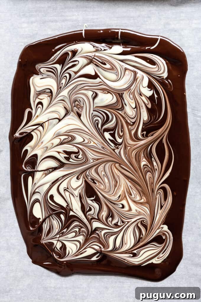 dark chocolate melted on a baking sheet with white chocolate swirls on it