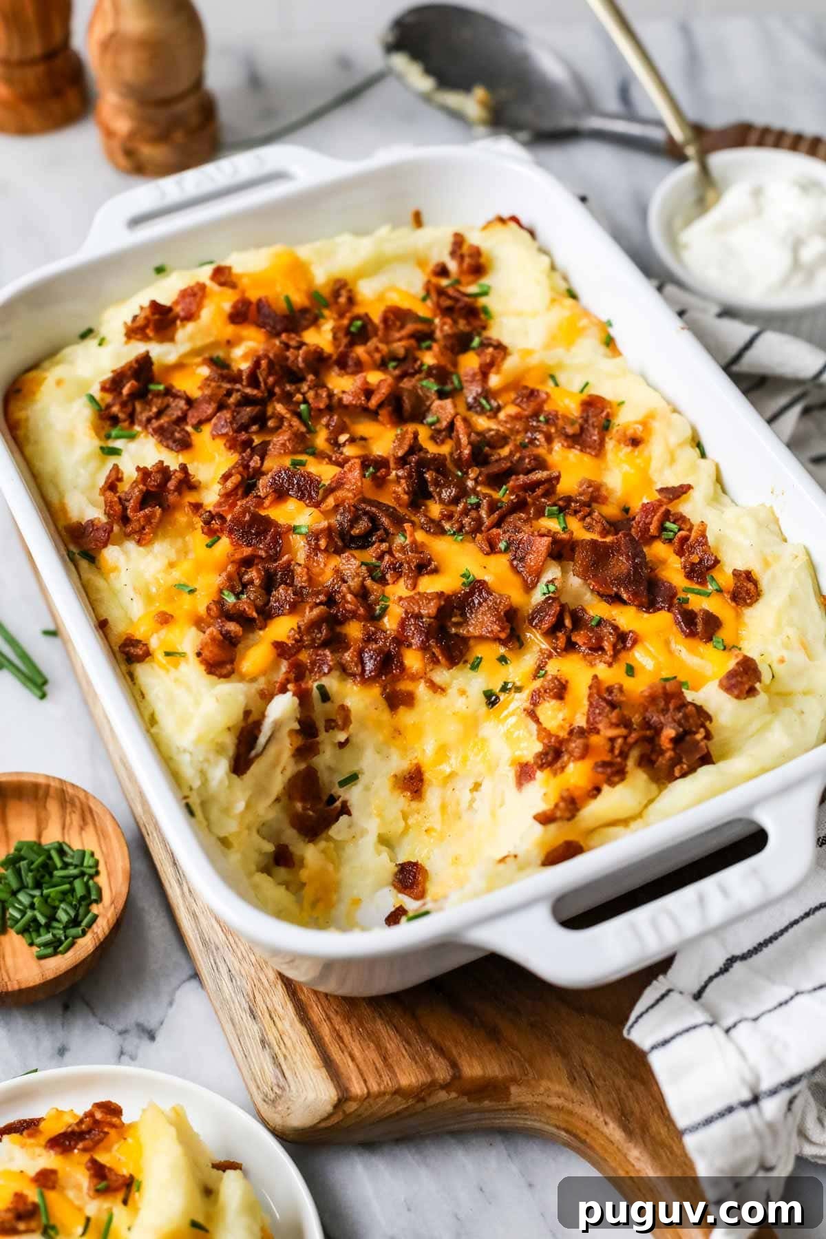 Cheesy Bacon Loaded Mashed Potato Casserole Recipe 2 Dish of loaded mashed potato casserole with one serving missing.