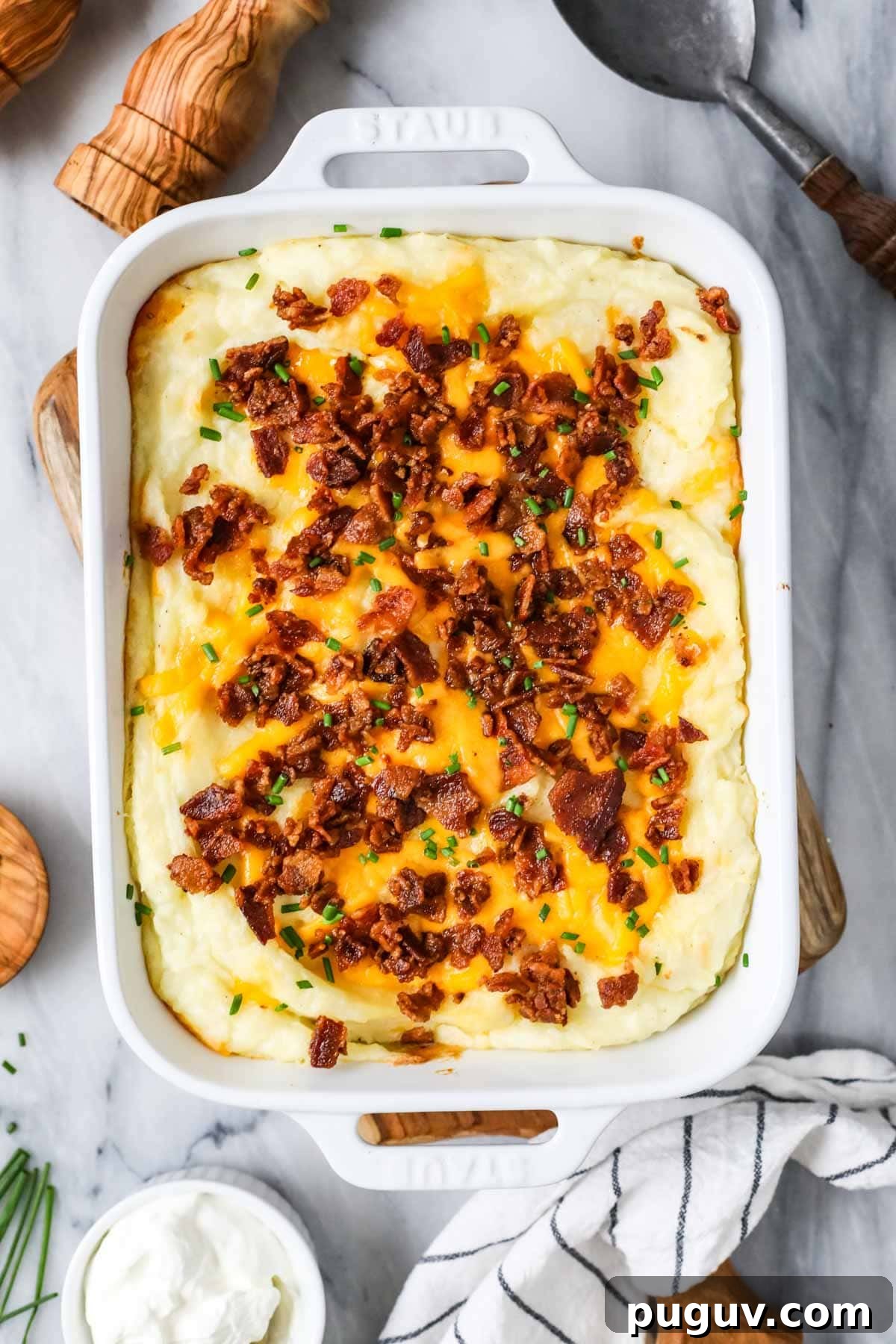 Cheesy Bacon Loaded Mashed Potato Casserole Recipe 6 Overhead view of a casserole made with mashed potatoes, cheese, bacon, and chives.