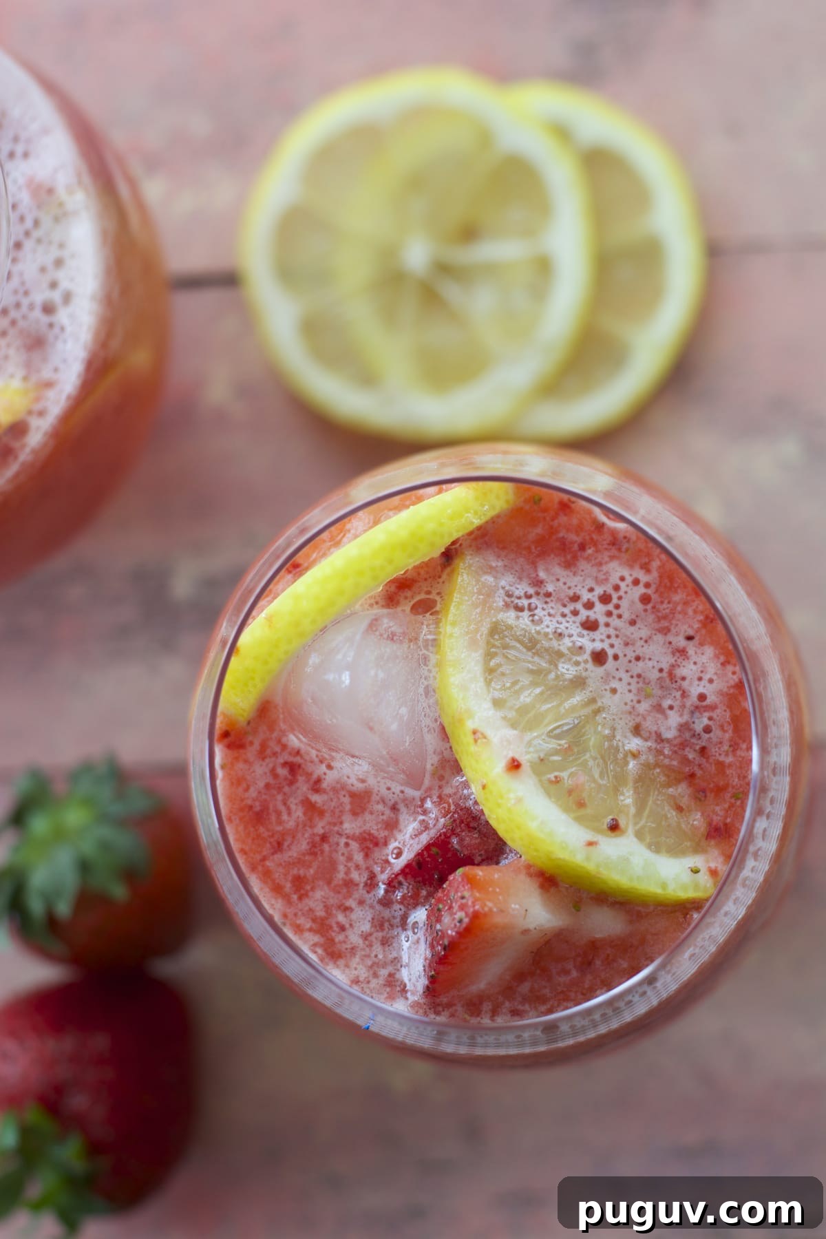 overhead shot showing a glass of strawberry lemonade garnished with extra strawberries and lemon slices