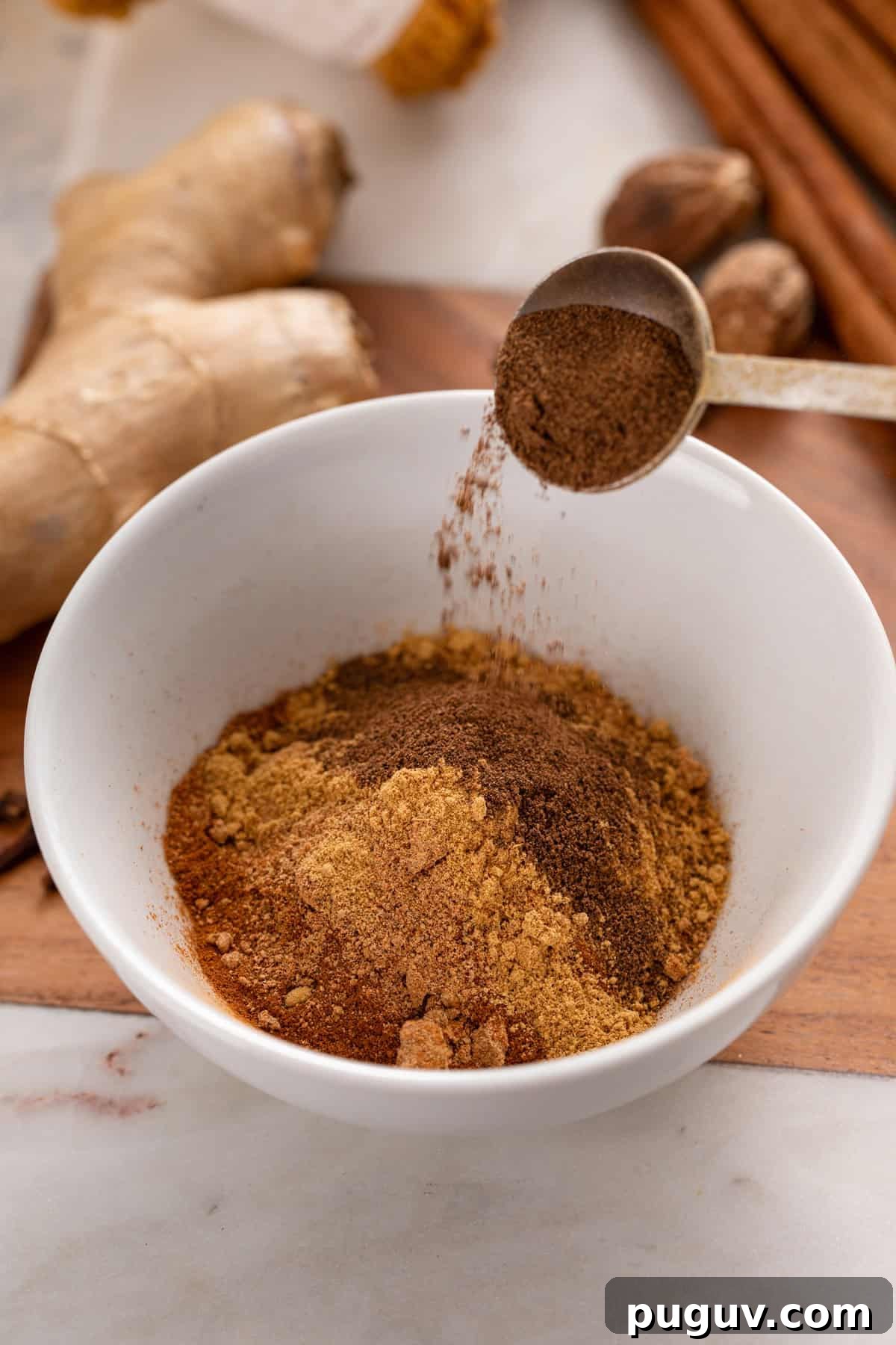 How to Make Pumpkin Pie Spice at Home for Cozy Fall Baking 5 Spices for pumpkin pie spice being added to a small white bowl.