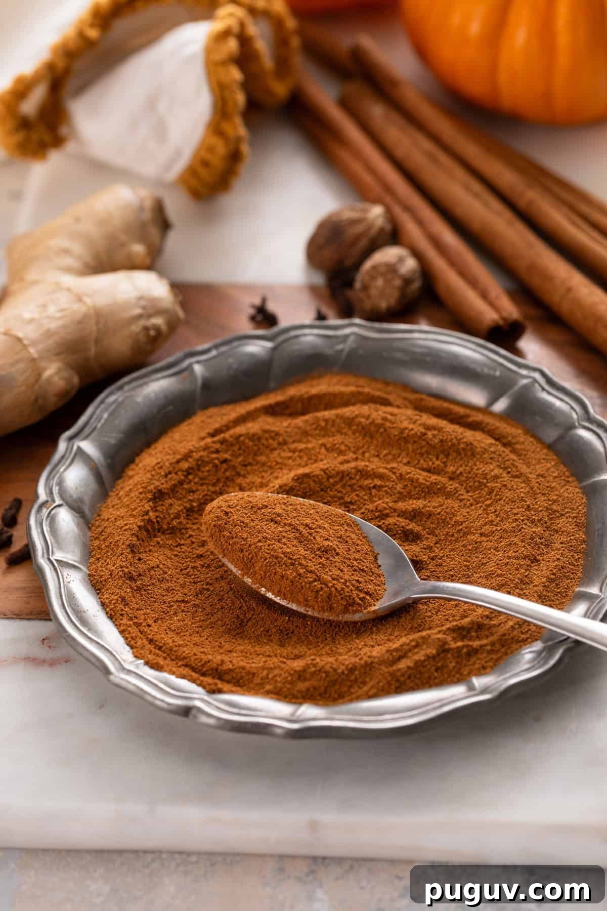 How to Make Pumpkin Pie Spice at Home for Cozy Fall Baking 8 Spoon of pumpkin pie spice resting on a metal plate.