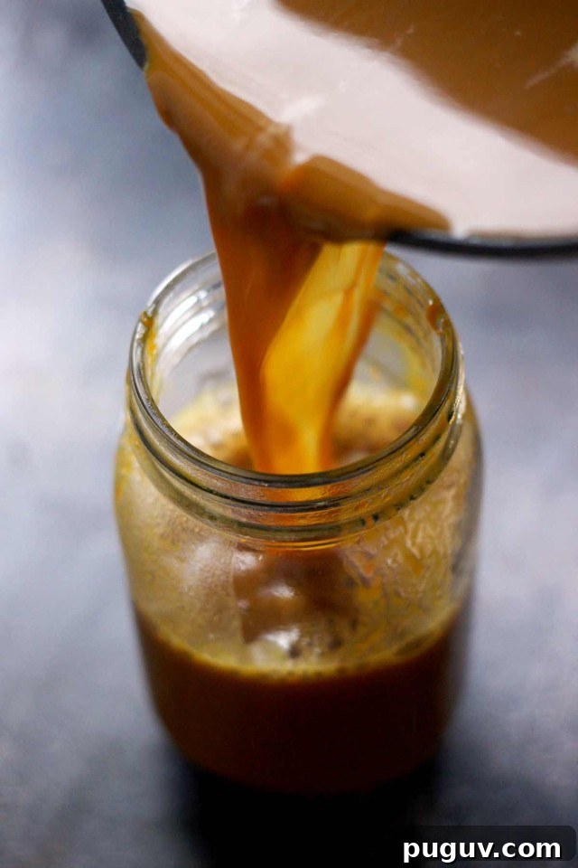 Healthy Vegan Pumpkin Spice Latte Being Poured into a Mason Jar Stnaind on the Table