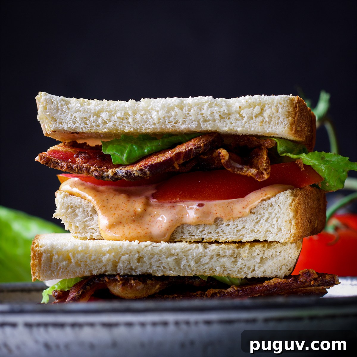 Two halves of a BLT sandwich on a plate, ready to eat.