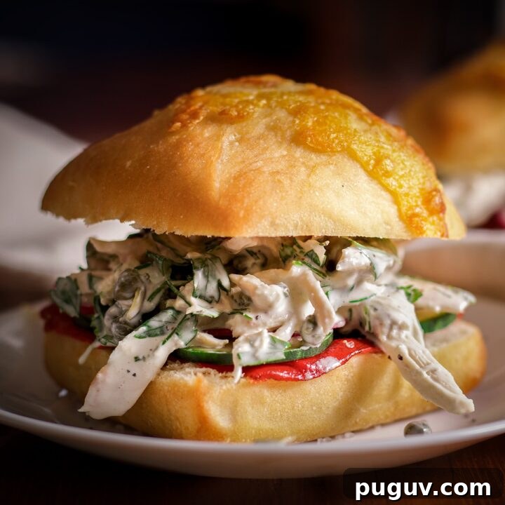A Mediterranean chicken salad sandwich on a white plate.