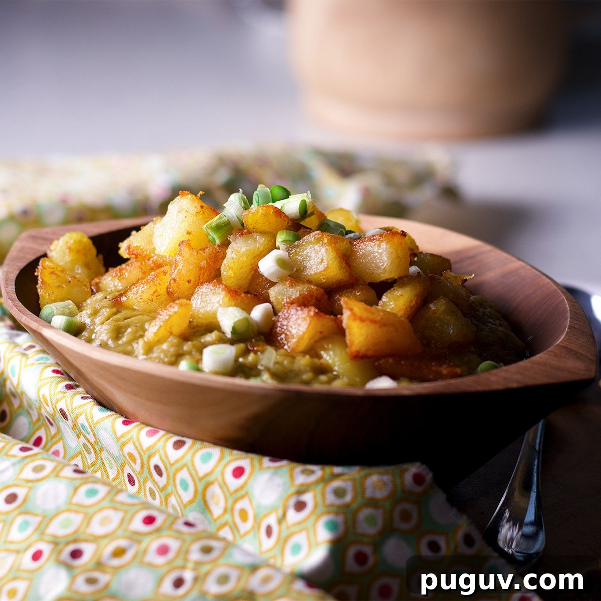 Truffled Fried Potatoes with Creamy Split Pea Soup 3 A wood bowl filled with split pea soup topped with truffle fried potatoes.
