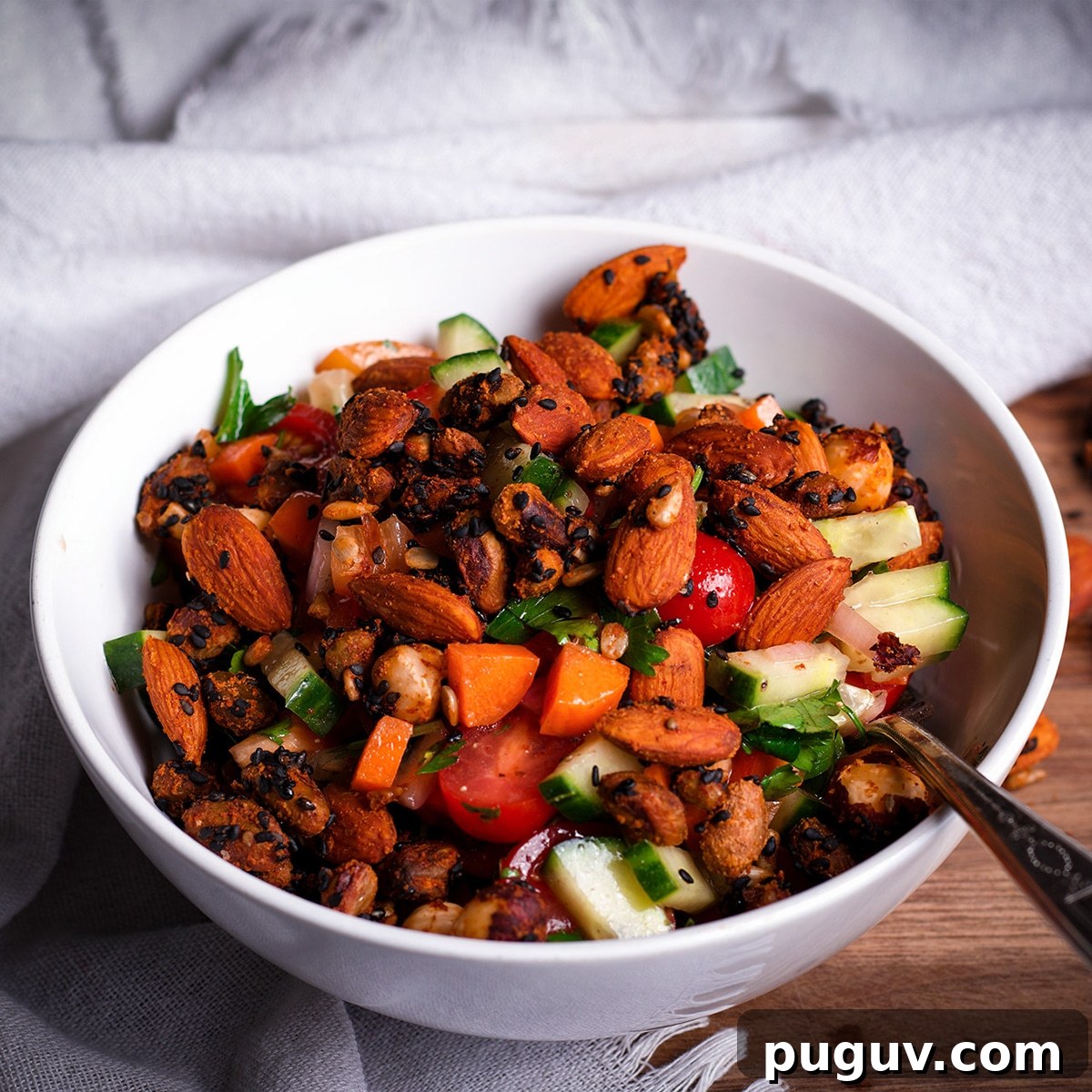 A bowl of Israeli Salad topped with roasted nuts and seeds.