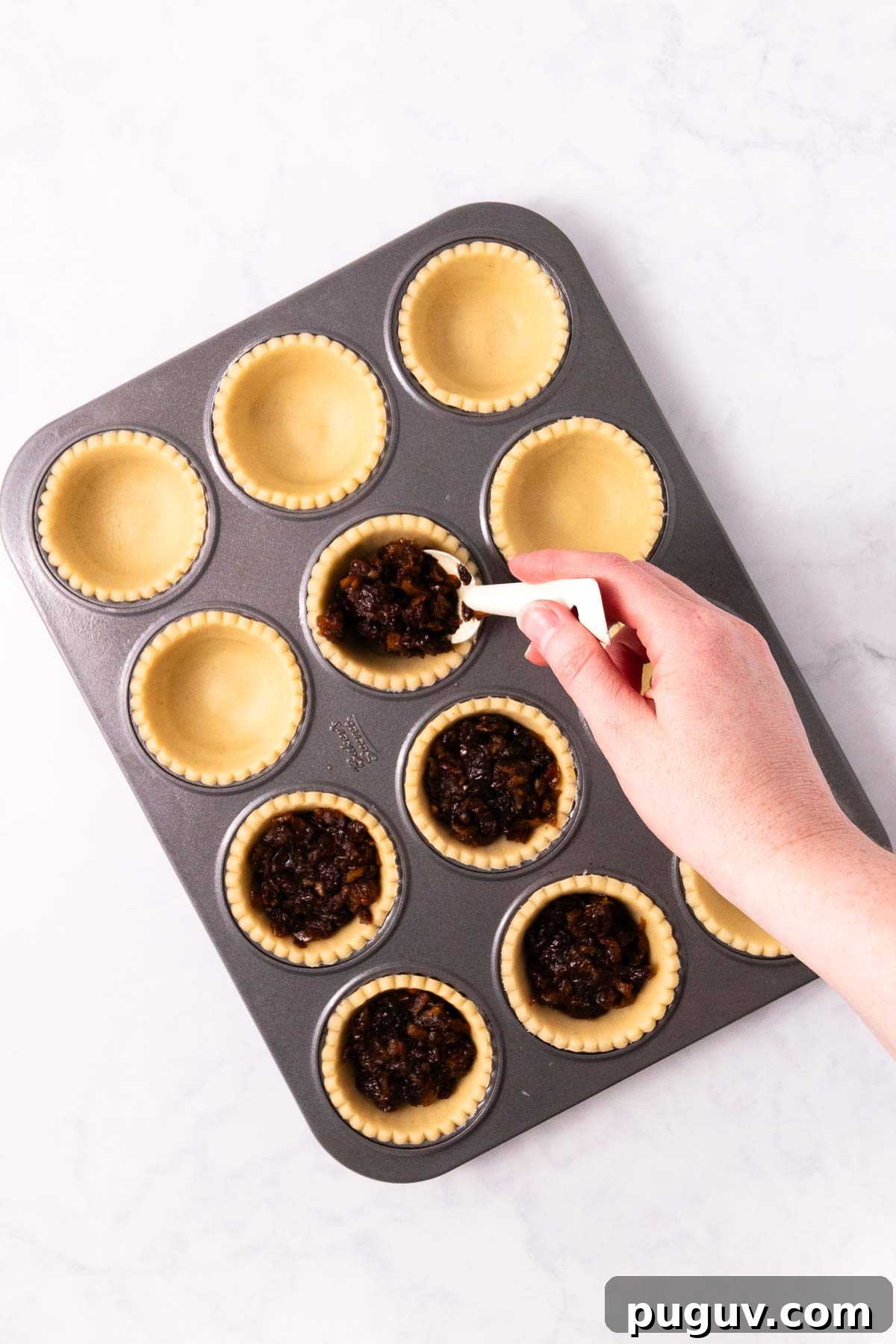 Spoon filling a pie case with mincemeat