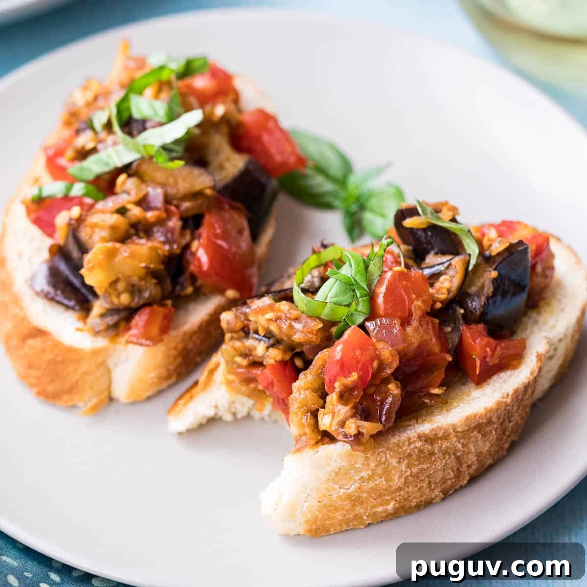 two eggplant bruschetta toasts on plate.