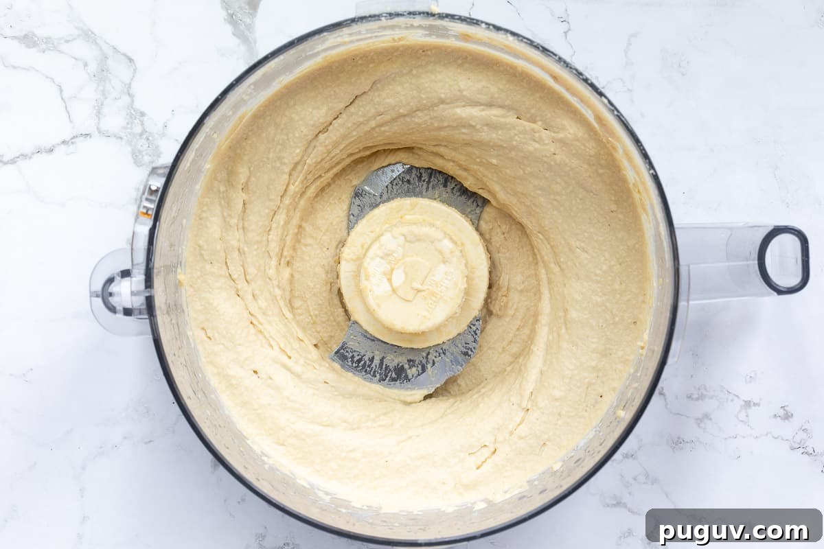Creamy Roasted Garlic Hummus Recipe for Smooth, Flavorful Dip 6 roasted garlic hummus in bowl of food processor.