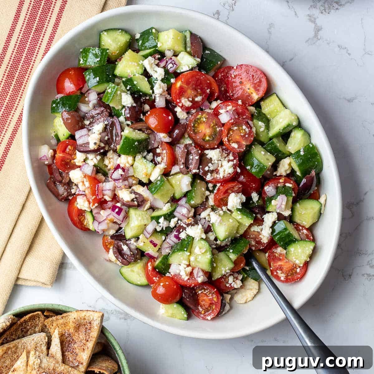 bowl of mediterranean cucumber tomato salad next to bowl of pita chips and napkin