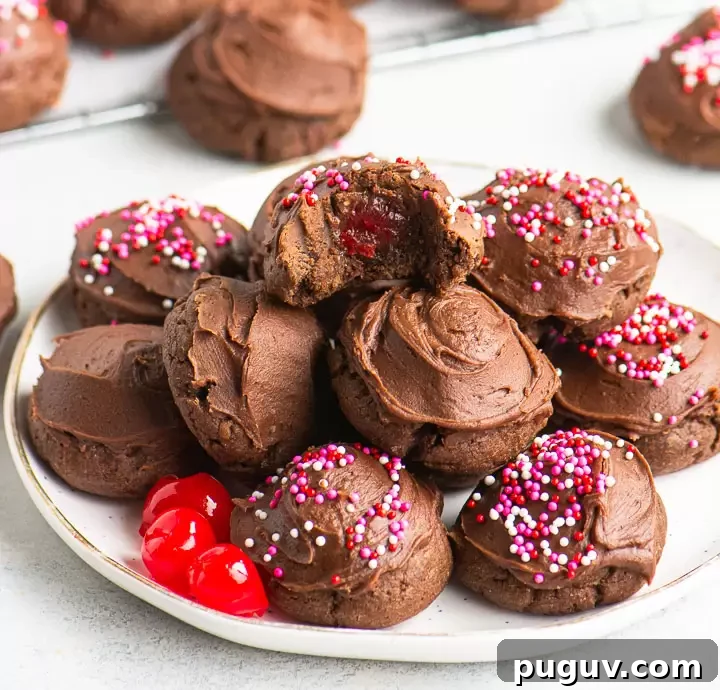 chocolate covered cherry cookies stacked on a plate with more cookies in the background