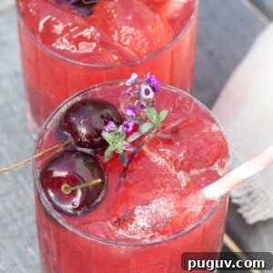A cherry gin soda with cherries, edible flowers and a stripy straw.