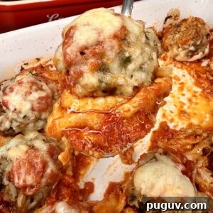 Italian-Style Baked Rice and Meatball Casserole 17 A close-up of a cheesy stuffed pepper being lifted from a baking dish, surrounded by several other stuffed peppers topped with melted cheese and tomato sauce.