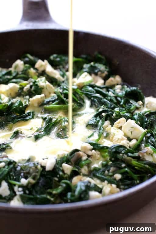 Spinach, Leek & Feta Frittata Recipe for Brunch or Dinner 4 Photo of egg mixture being poured over spinach and leek combination in cast iron skillet.