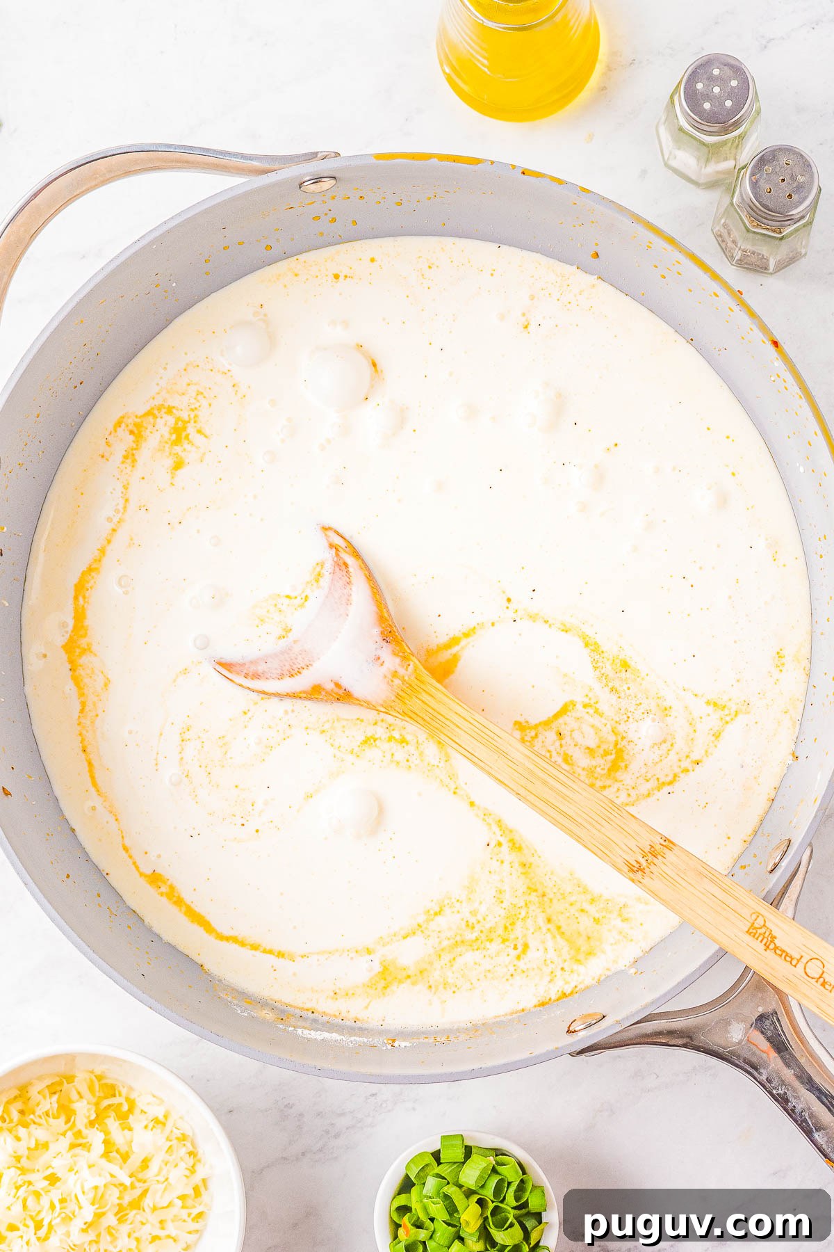 Cream sauce being whisked in a skillet.