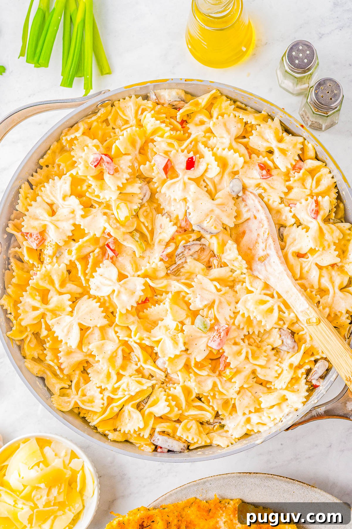 Pasta being tossed in a vegetable cream sauce.