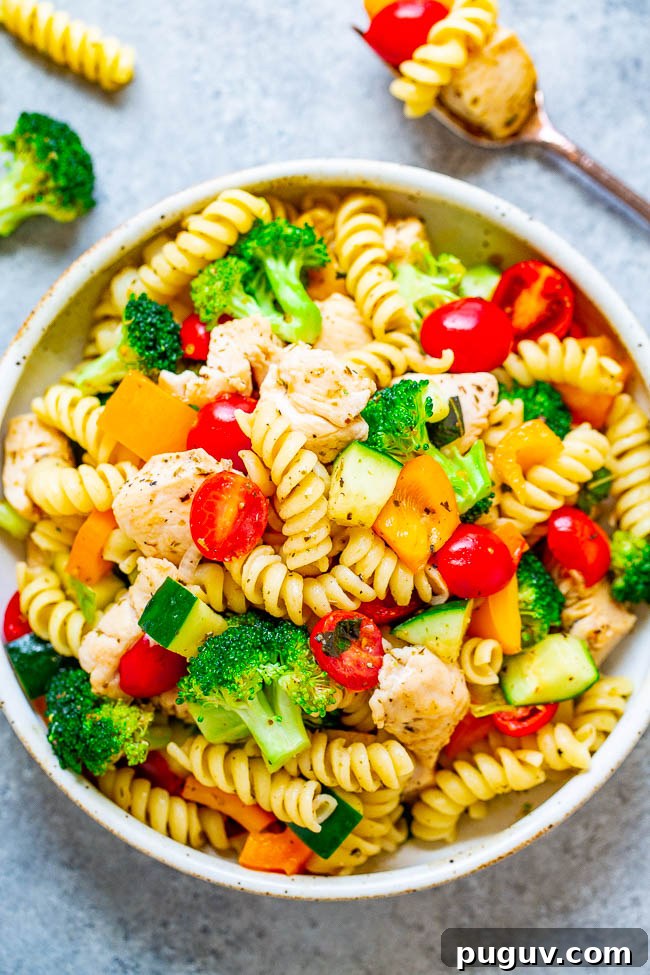 A vibrant bowl of chicken pasta salad with broccoli, cherry tomatoes, and bell peppers.