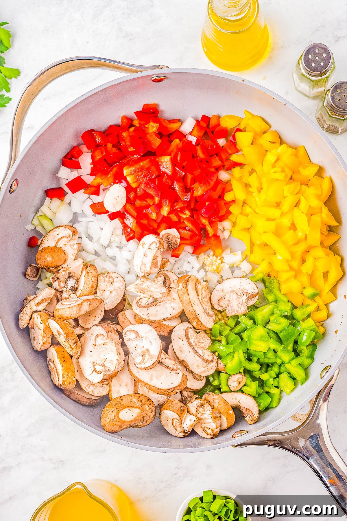 Red, yellow, and green bell peppers, mushrooms, and onions in a skillet.
