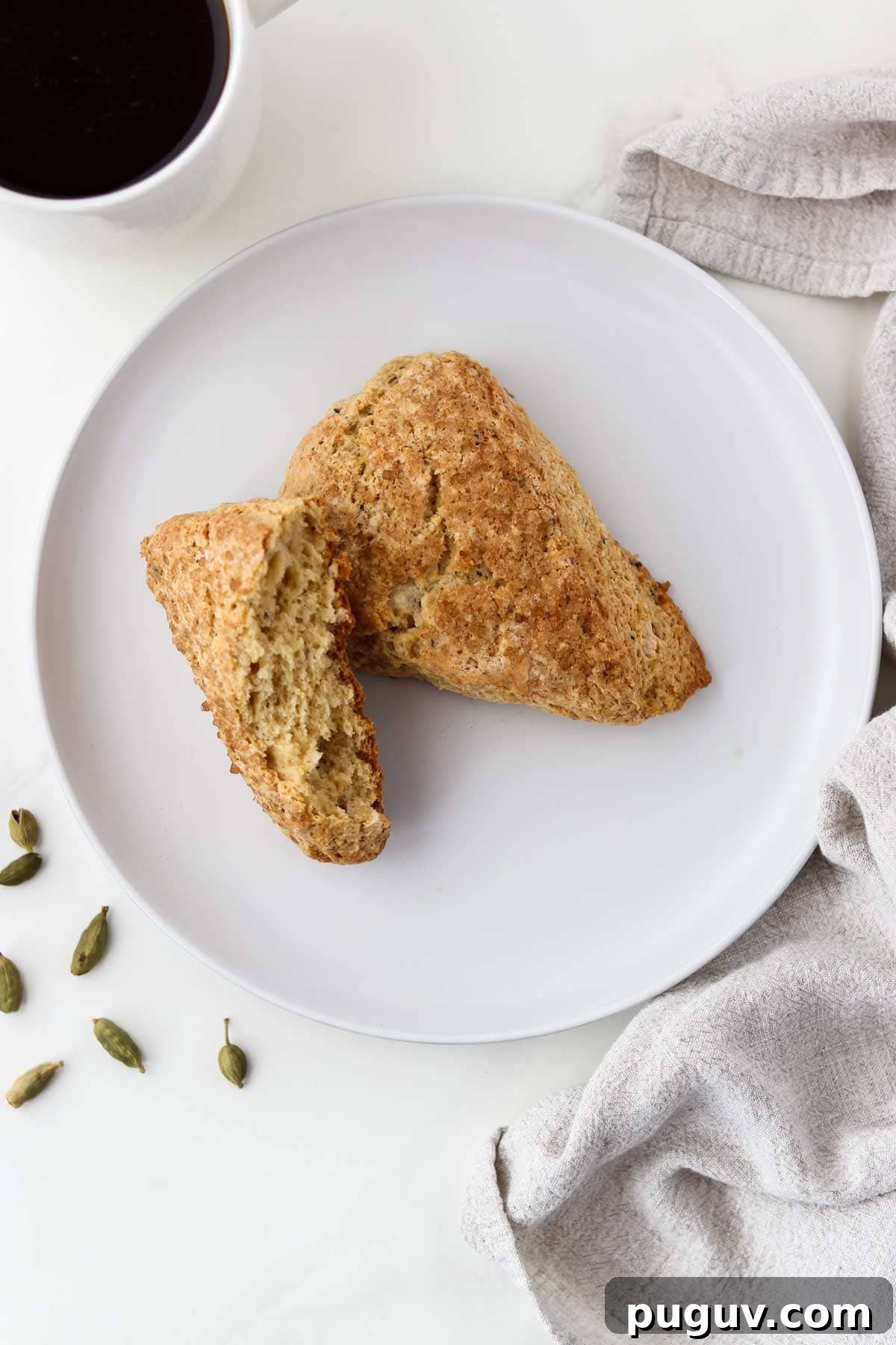 Brown Sugar Cardamom Scones Recipe for Tender, Buttery Pastries 2 Overhead view of cardamom scones next to a cup of coffee and cardamom pods.