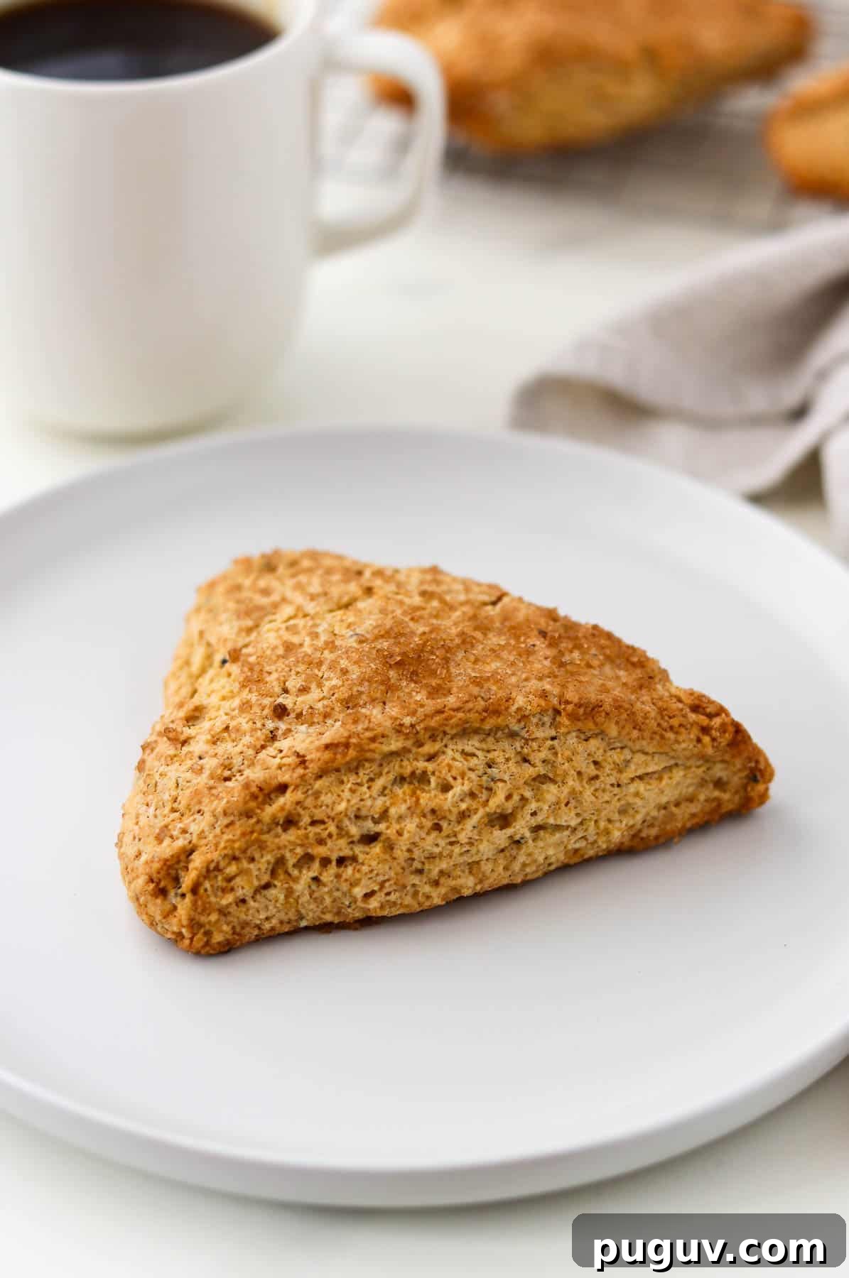Brown Sugar Cardamom Scones Recipe for Tender, Buttery Pastries 12 Brown Sugar Cardamom Scone on a white plate next to a cup of coffee.