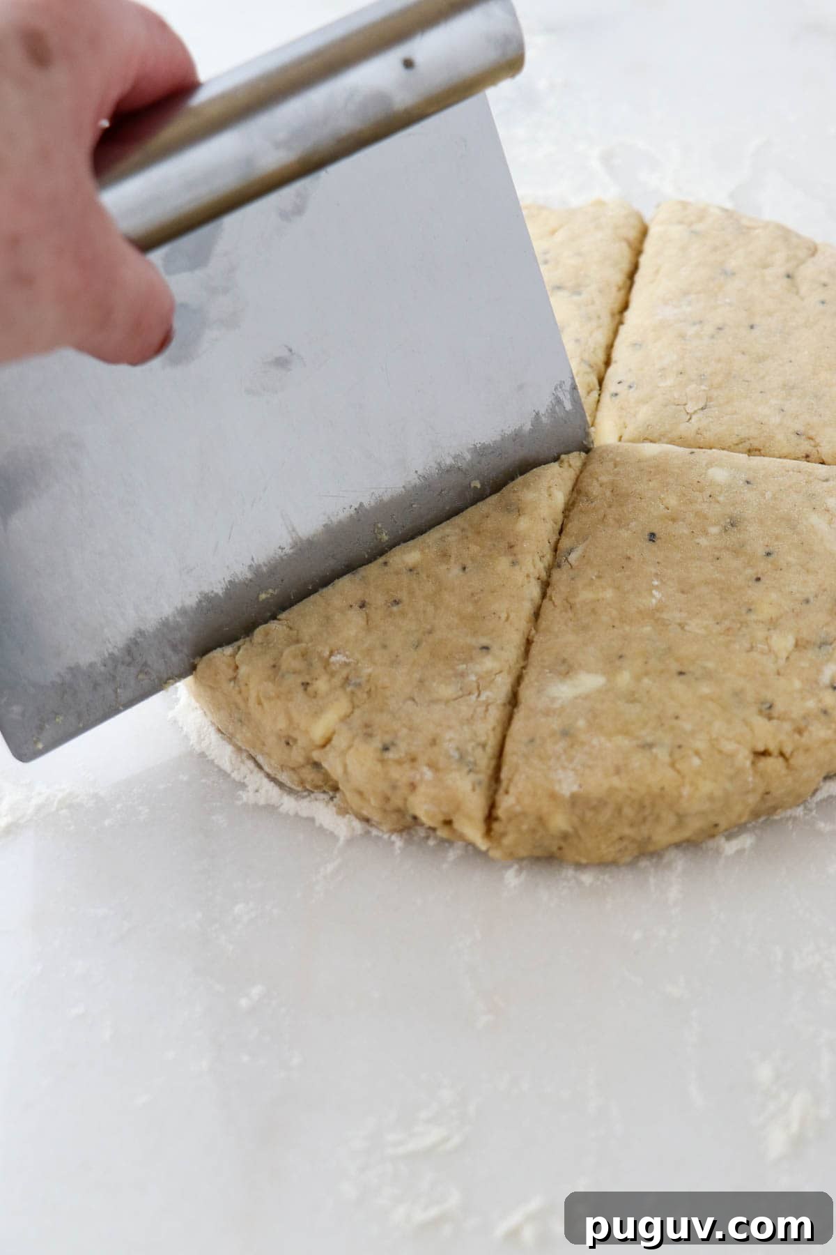 Brown Sugar Cardamom Scones Recipe for Tender, Buttery Pastries 8 Person cutting scone dough with a dough scraper.