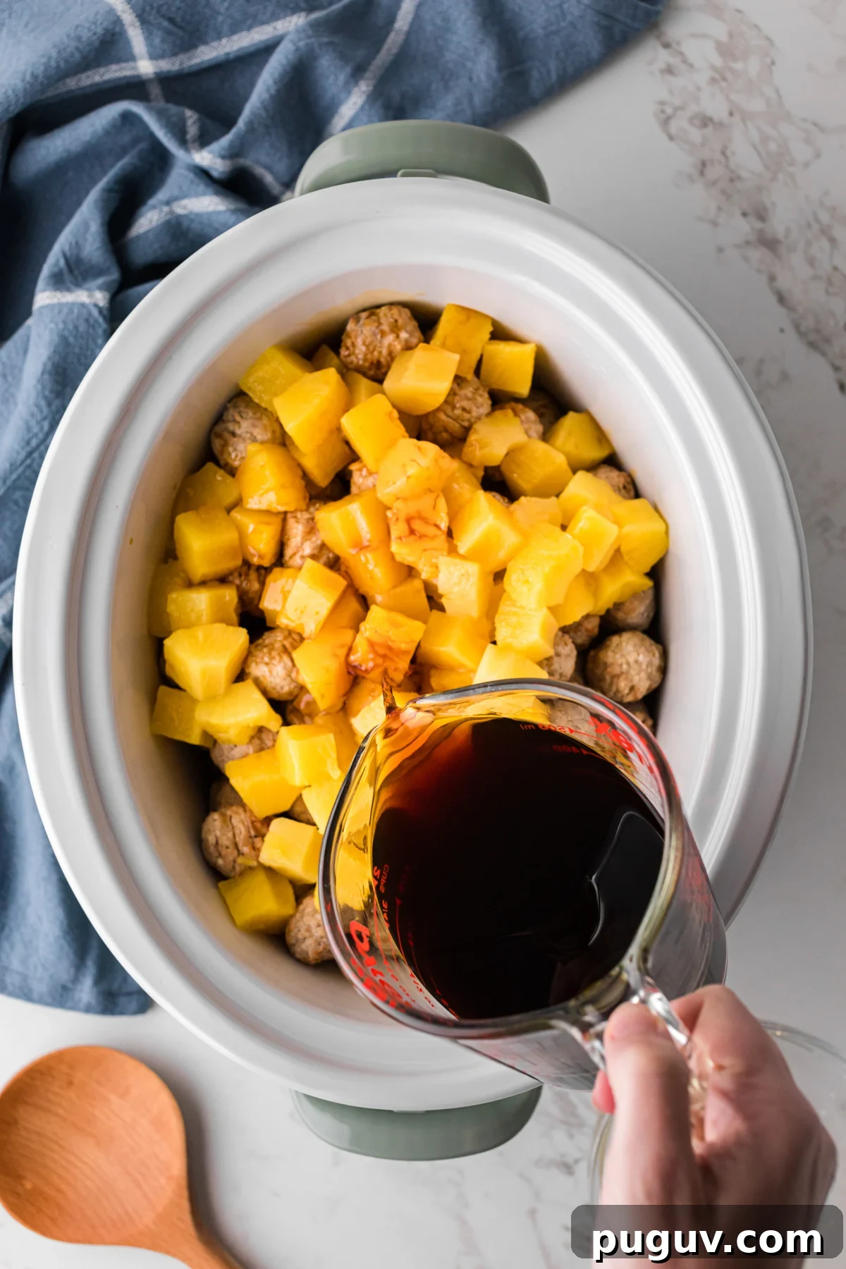 Pineapple chunks and teriyaki sauce added to frozen meatballs in a slow cooker.