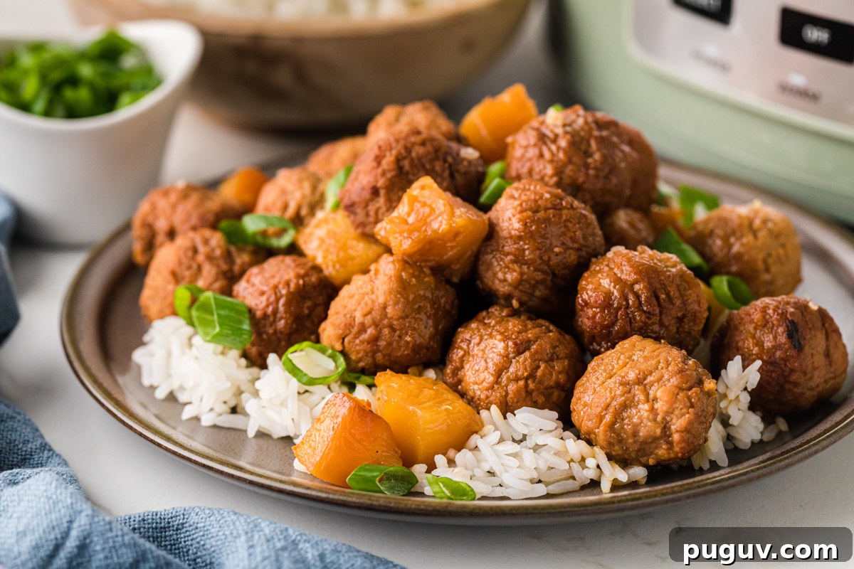 A serving of pineapple meatballs over white rice on a plate.