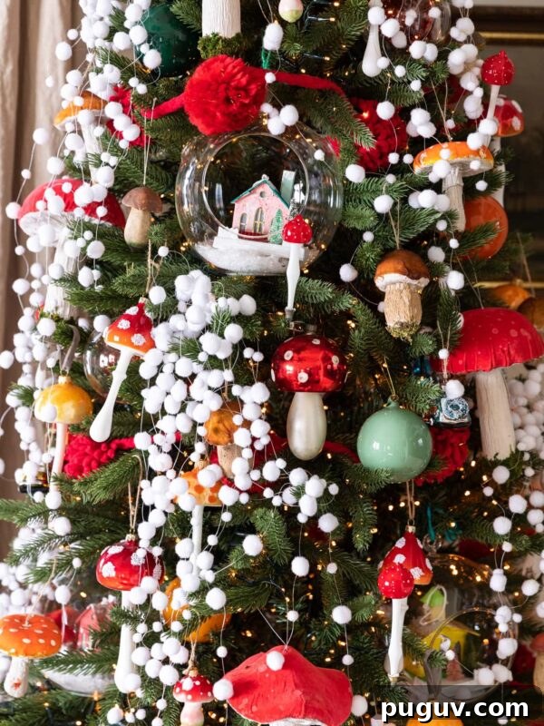 Red colored mushroom ornaments dangling from Christmas tree covered with white fake snow garland