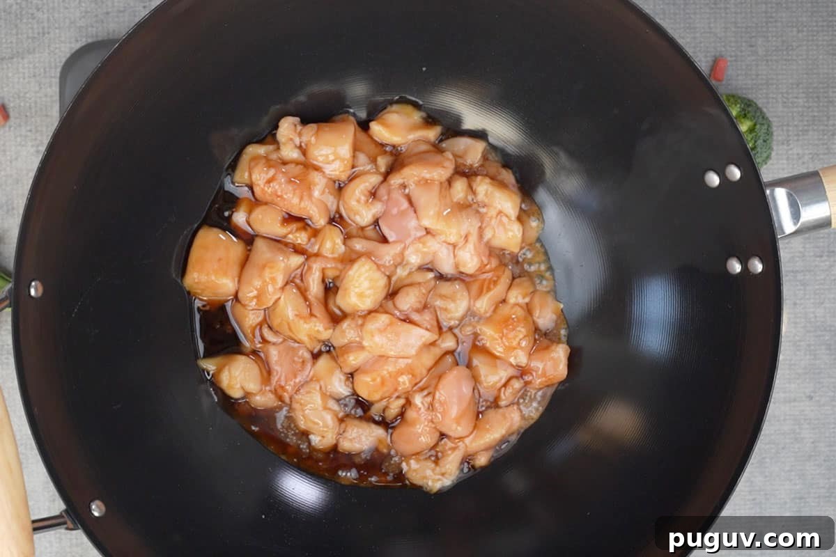 Chicken added to a wok.