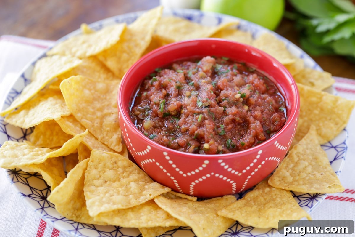 Fresh homemade salsa in a small bowl alongside of tortilla chips.