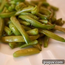 Slow simmered green beans on a white dish.