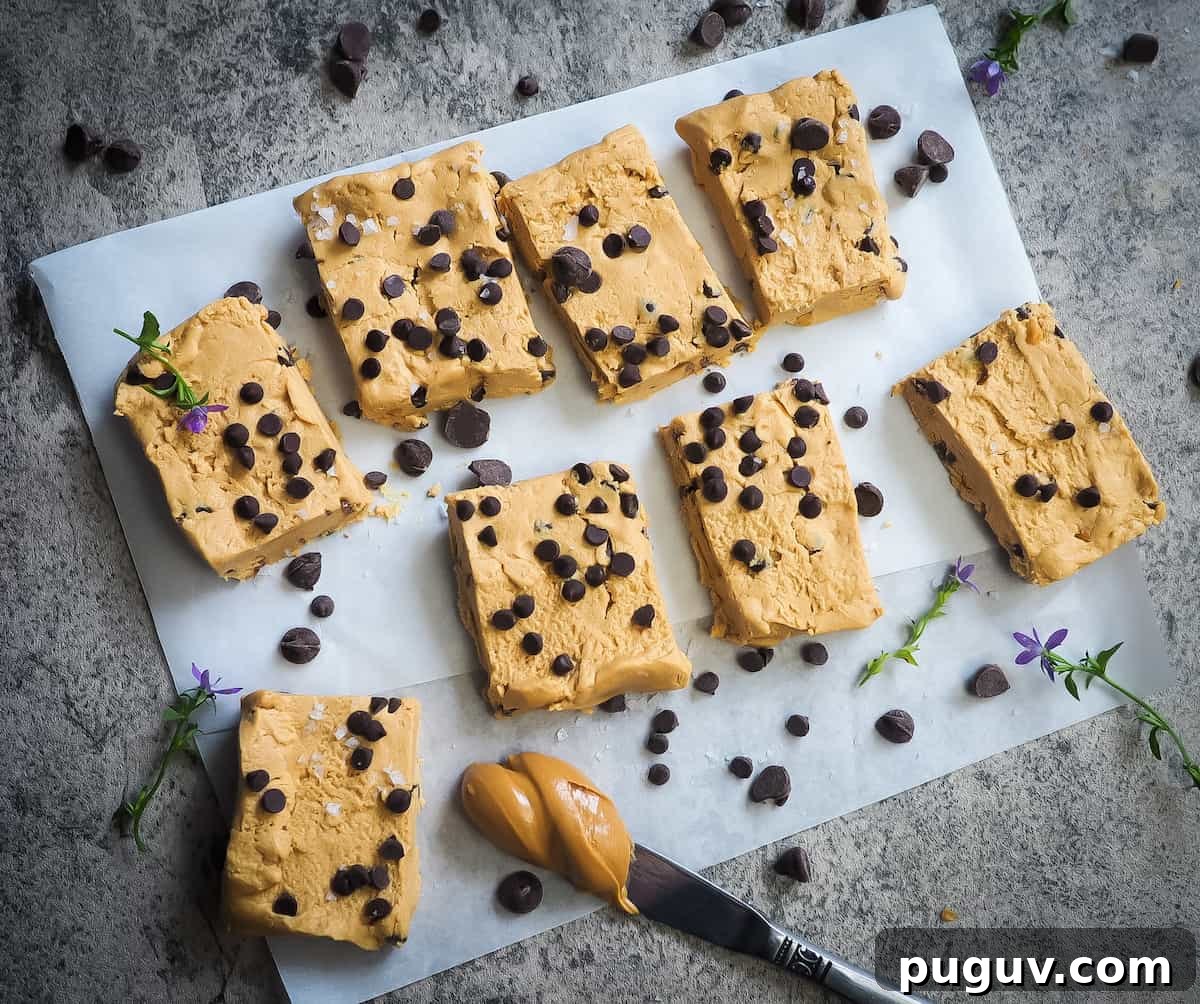 Peanut butter and chocolate chip perfect bars on a piece of parchment paper with a knife and a glob of peanut butter.