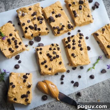 Peanut butter and chocolate chip perfect bars on a piece of parchment paper with a knife and a glob of peanut butter.