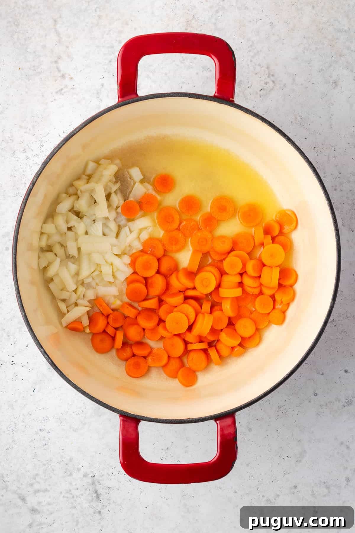 Onions and carrots being sauteed in melted butter in a large pot.