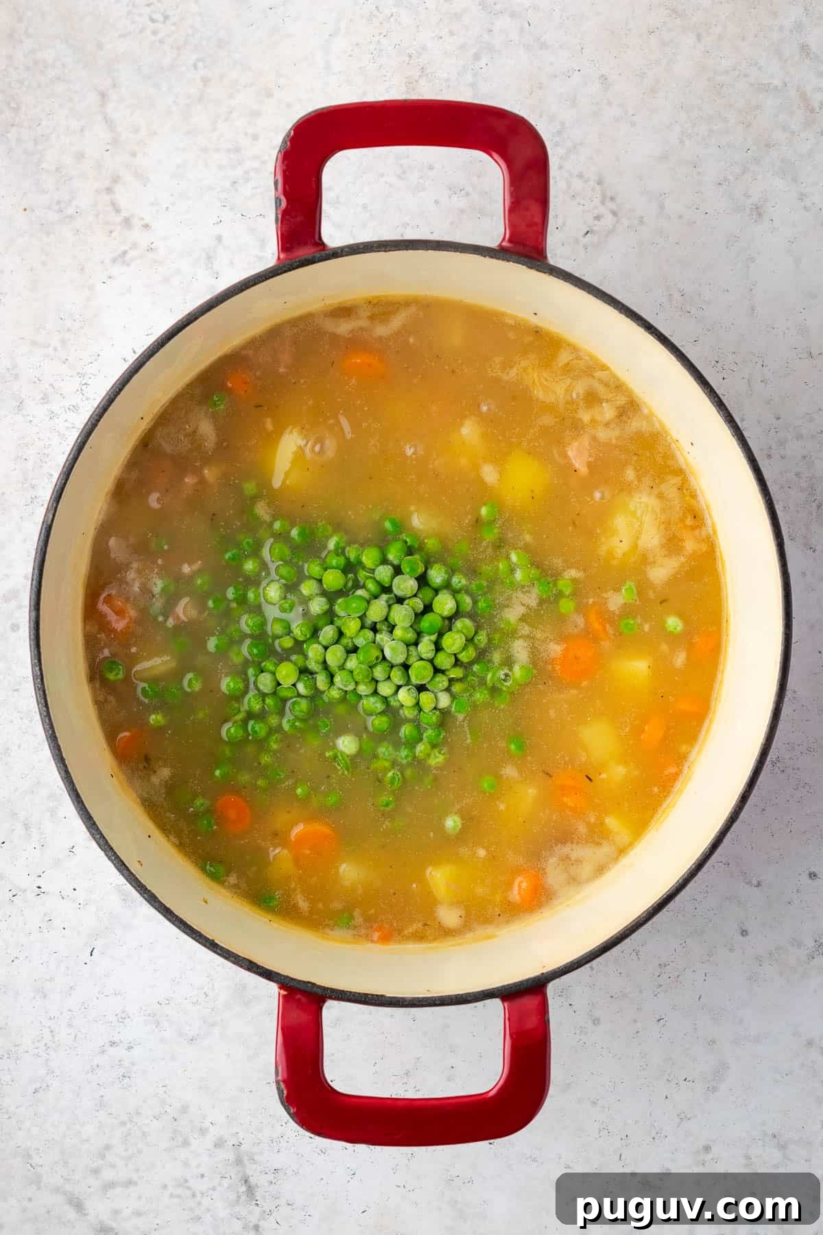 Frozen green peas being added to the cooked ham and potato soup.