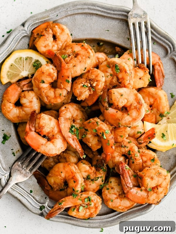 Large silver platter filled with well-seasoned Cajun shrimp garnished with chopped parsley and served with sliced lemon.