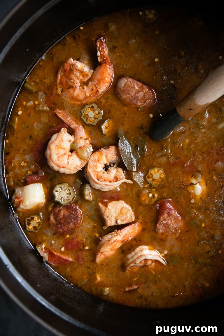 Large cast iron pot filled with chicken, sausage, and seafood filled gumbo recipe.