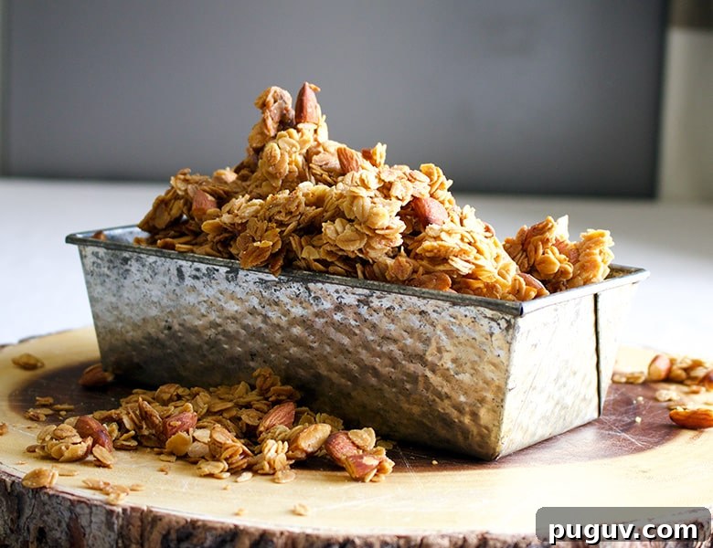 A tin loaf pan filled to overflowing with homemade maple almond granola.